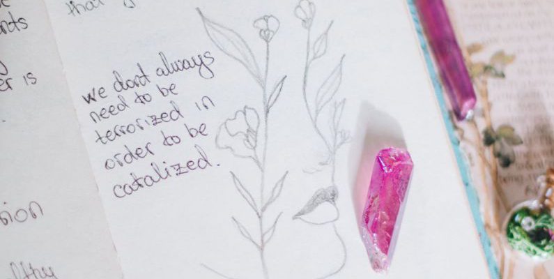 Alchemy - A notebook with a book and a pen on top of a table