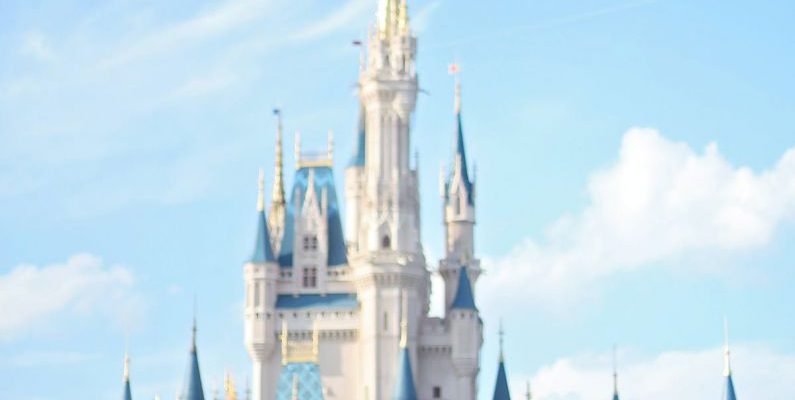 Day Trip - White fairy tale castle with blue roofs in amusement park in Orlando against bright sky on sunny day