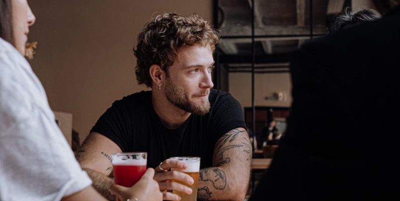 Beer - Photo of a Man with Curly Hair Holding a Glass of Beer